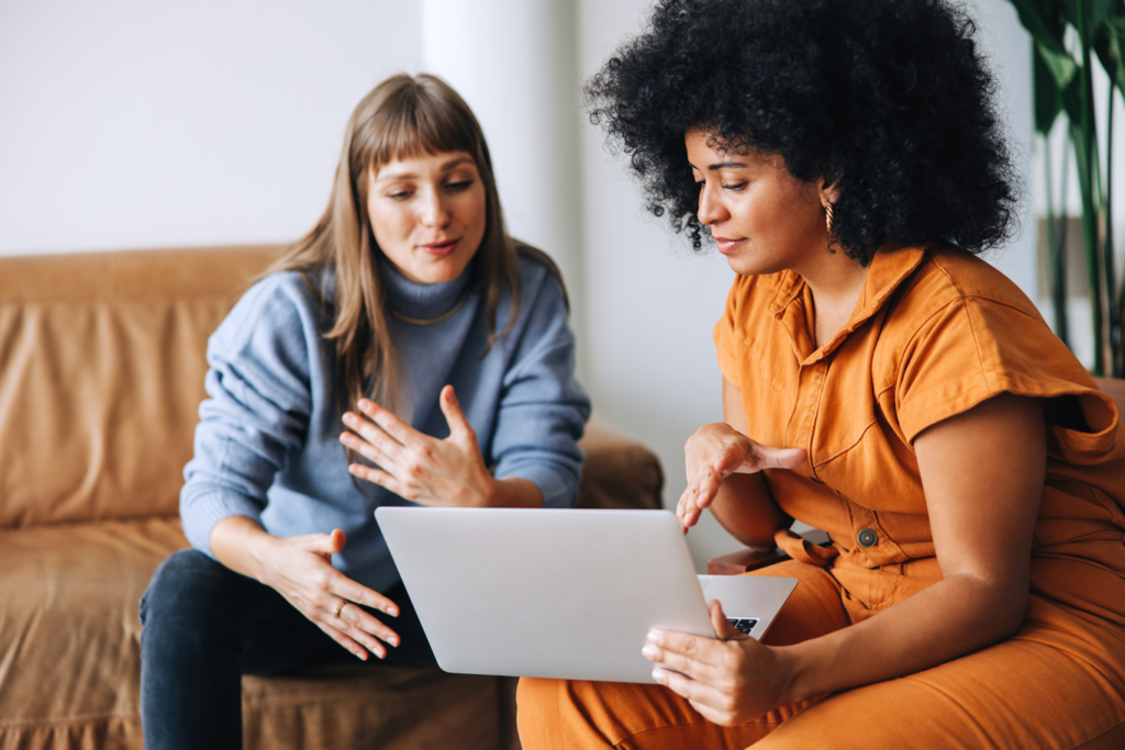 Professional woman using laptop and providing advice to another woman