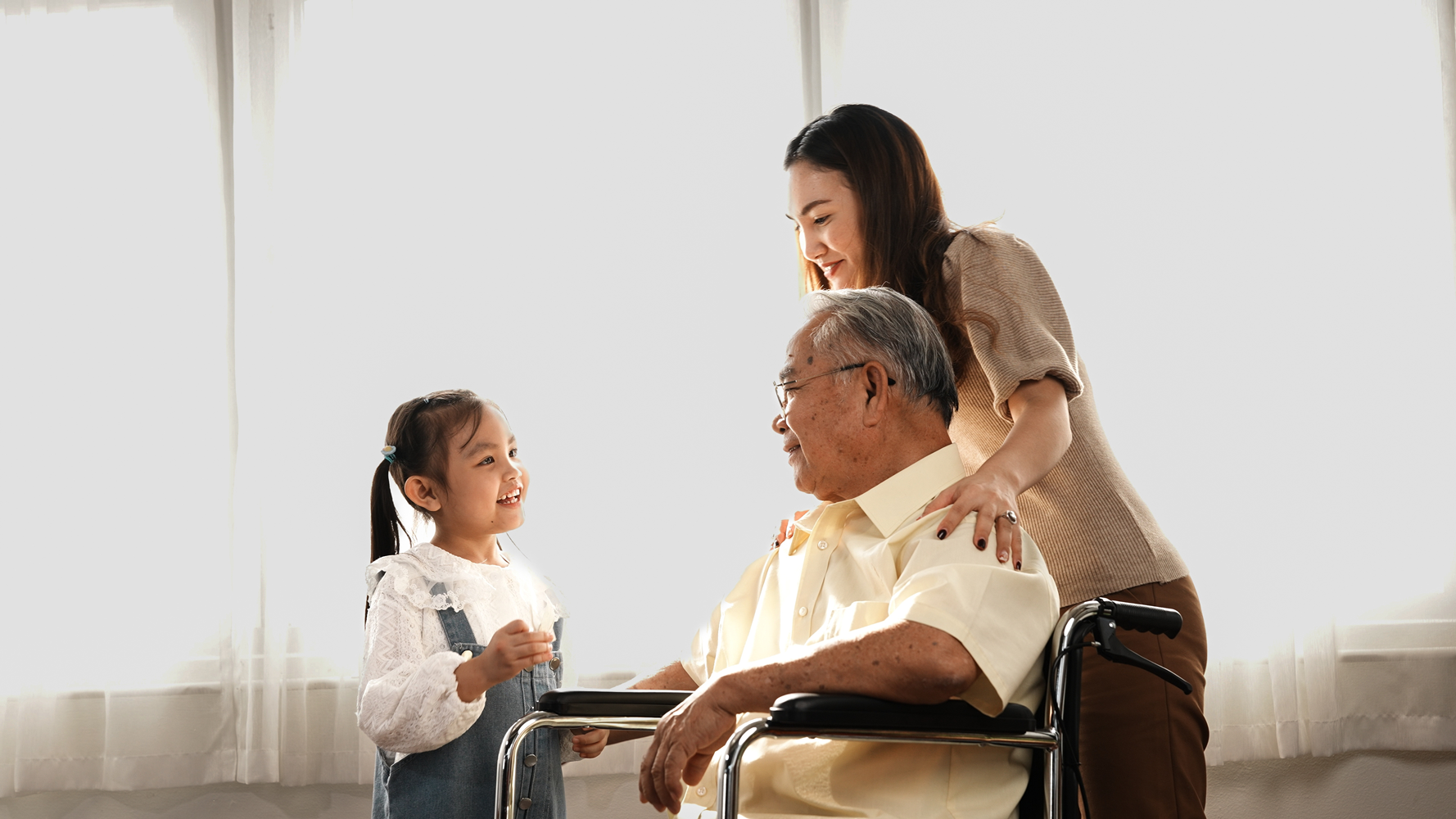 A woman and a child sitting in a wheelchair with an older man, family enjoying a day out together.