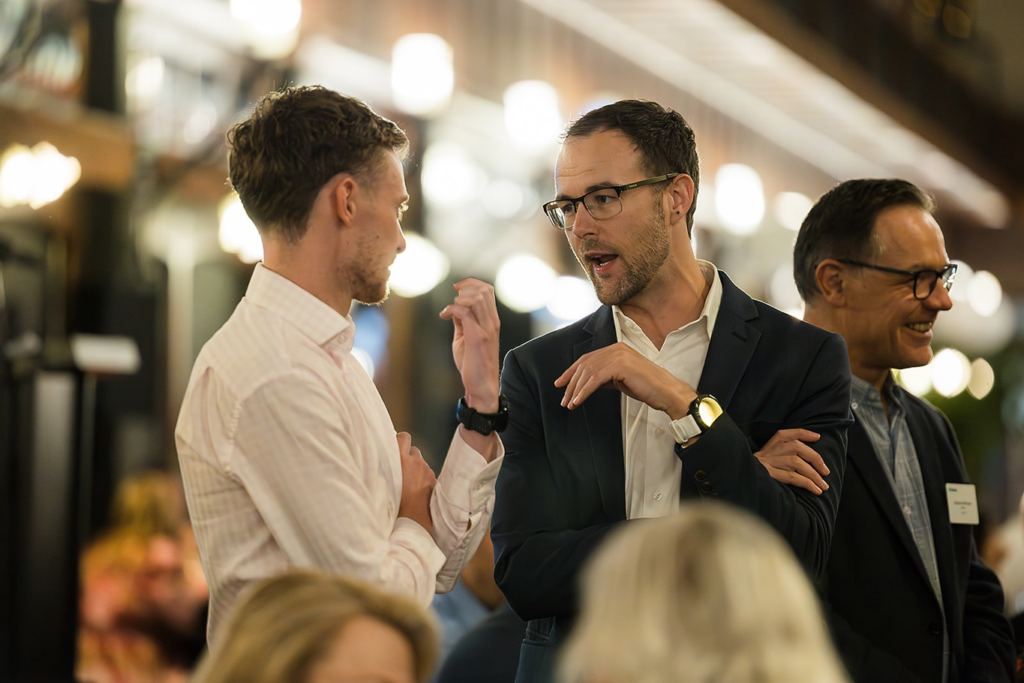 Two male colleagues at networking event discussing business