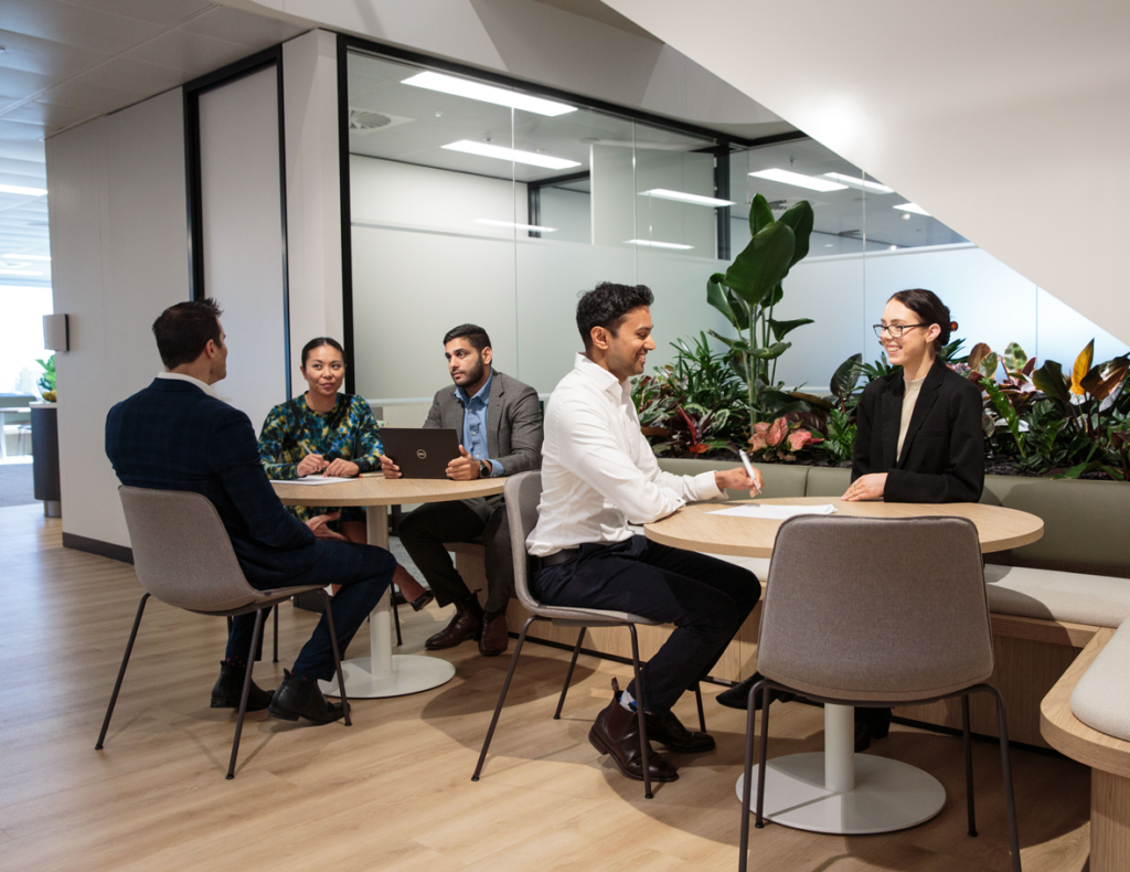 Multicultural team discussing business strategies while seated around a table in a corporate office.