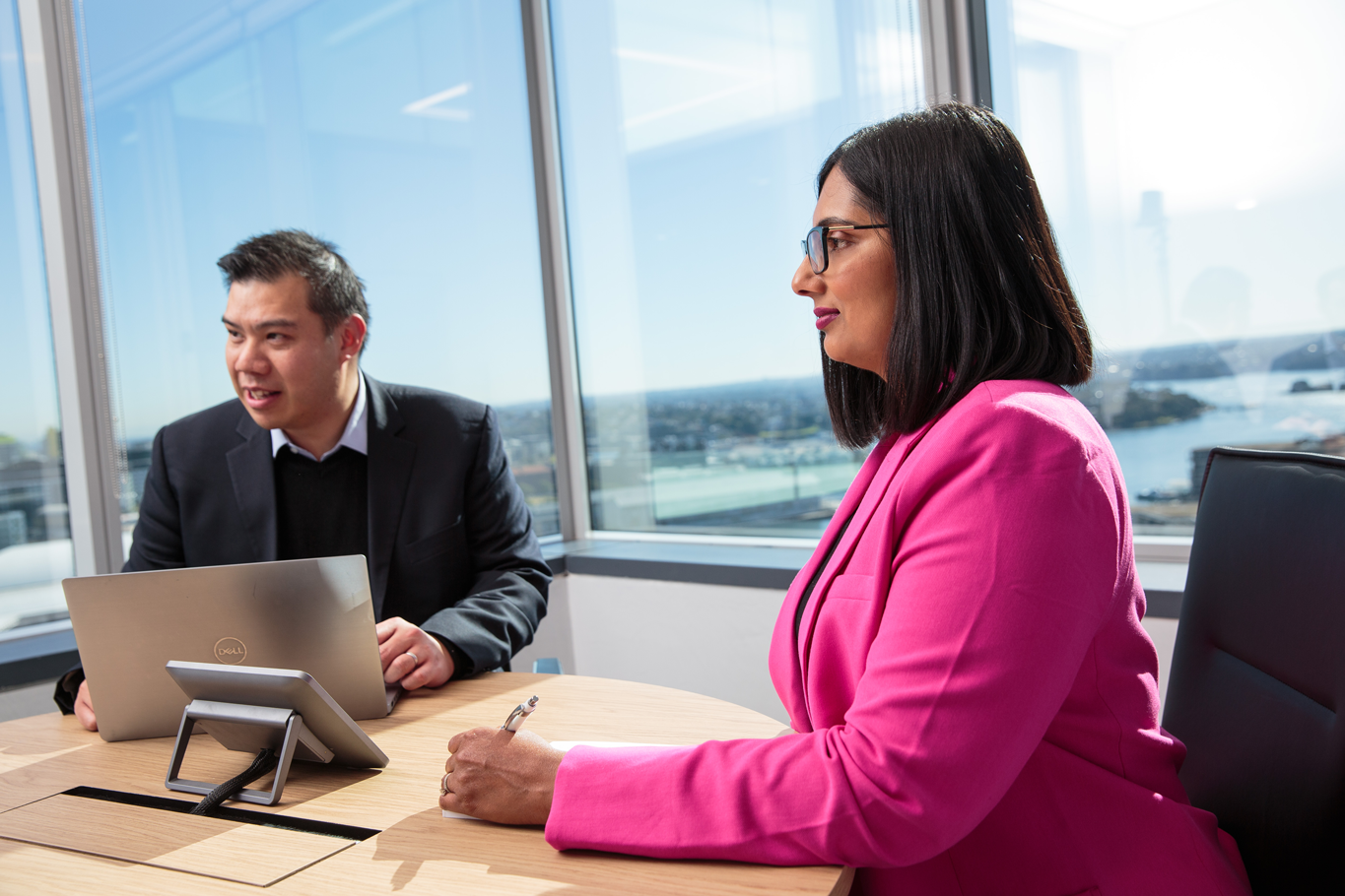 A man and a woman sitting at a table with a laptop, discussing family wealth