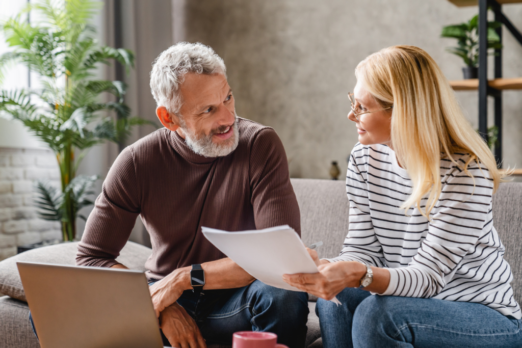 A middle aged couple on a couch, examining a family business document together.