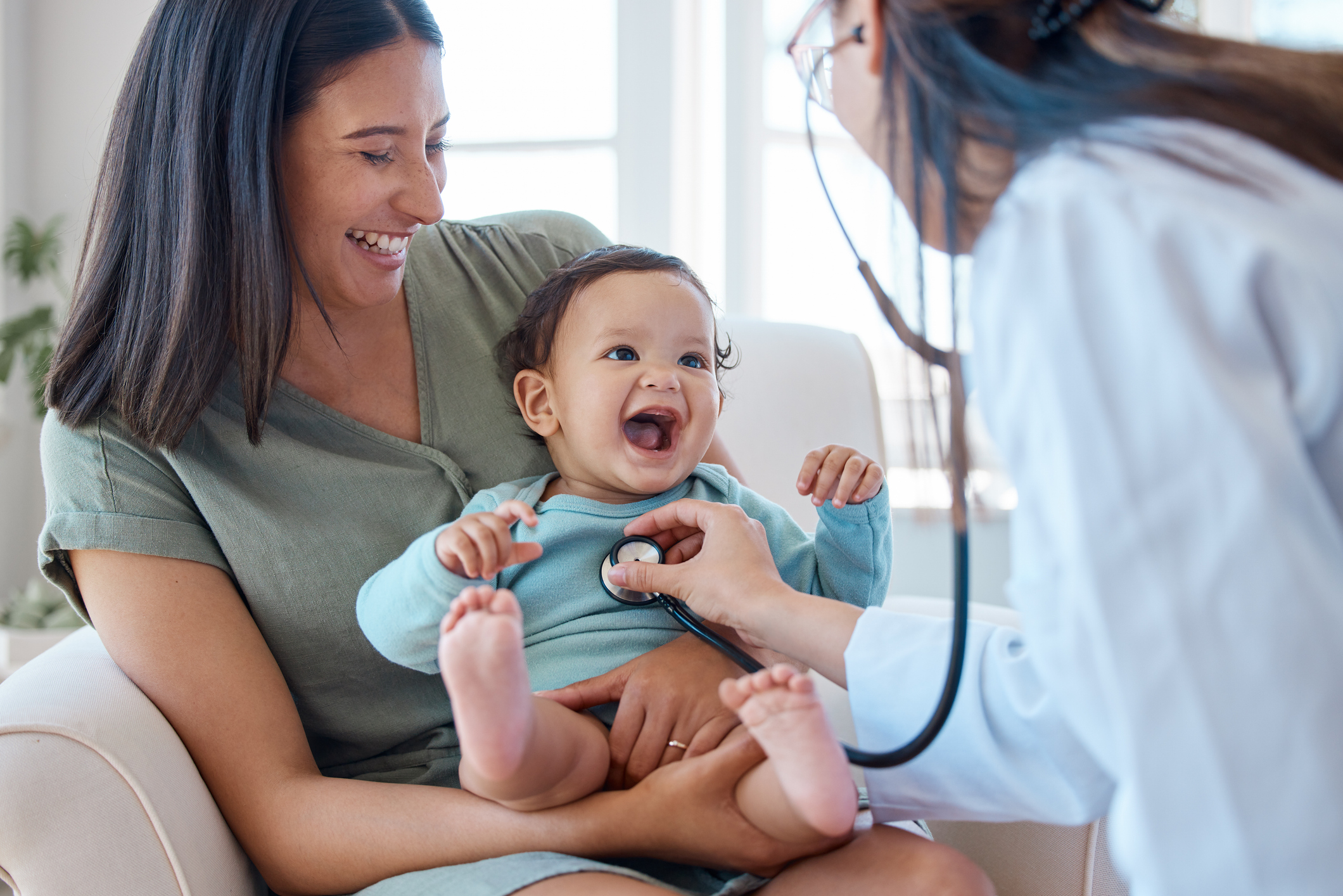 A woman holding a baby while a doctor examines the baby.