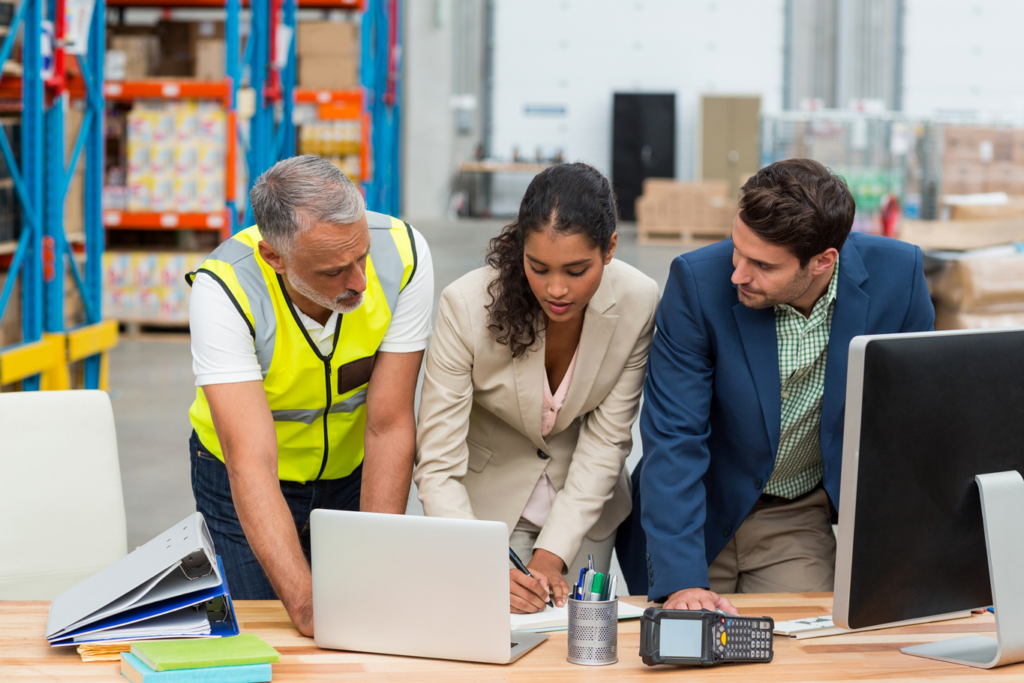 Warehouse managers and worker discussing with laptop in a warehouse office