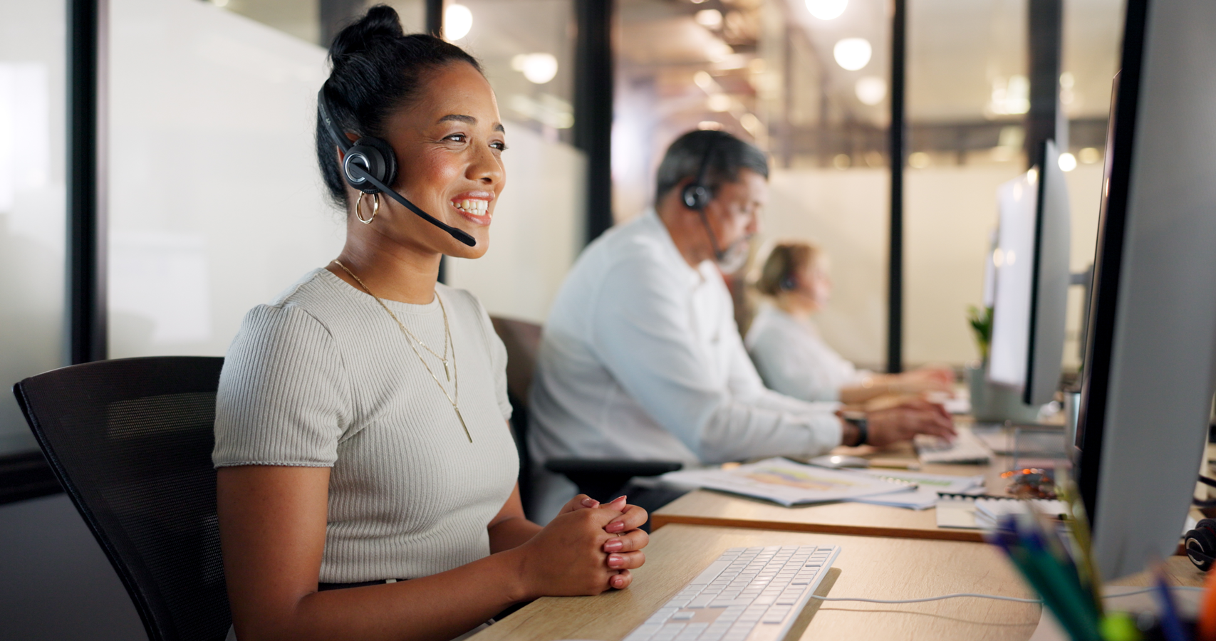 A woman wearing a headset while working at her desk in an office.