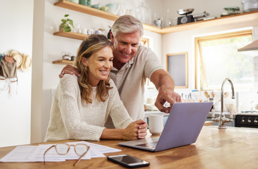 Middle-aged couple discussing financial affairs whilst looking at computer in their kitchen