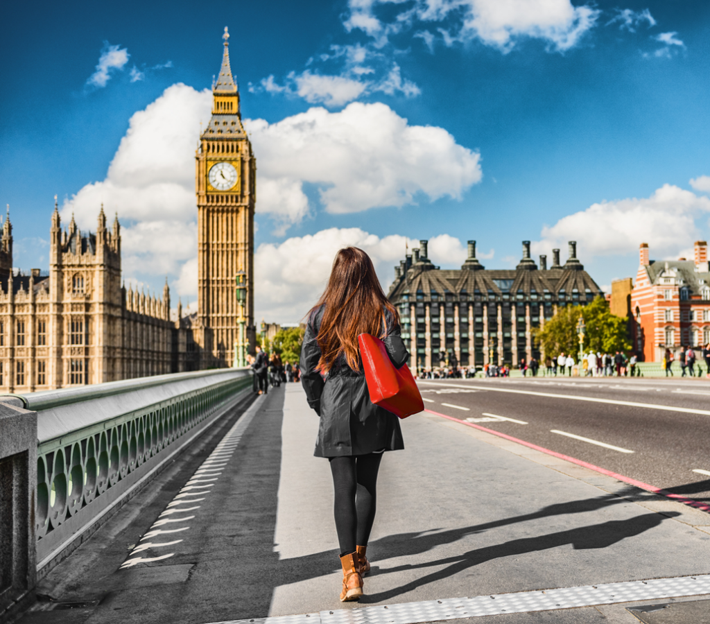 Woman with red bag walking over River Thames towards Big Ben in London, United Kingdom