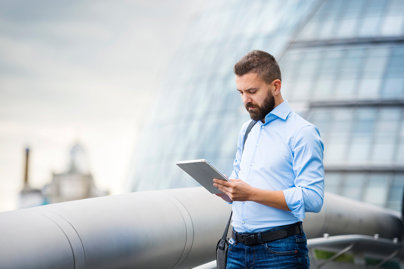 Business man on tablet outside of office building in London, United Kingdom