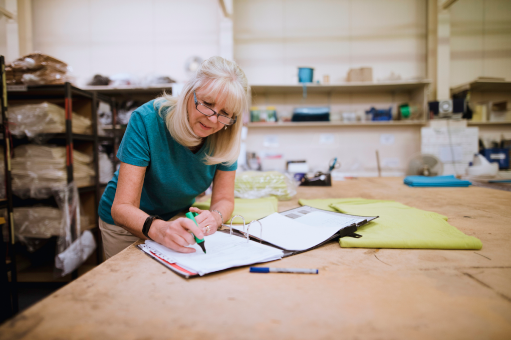 A woman writing on a paper in a factory.