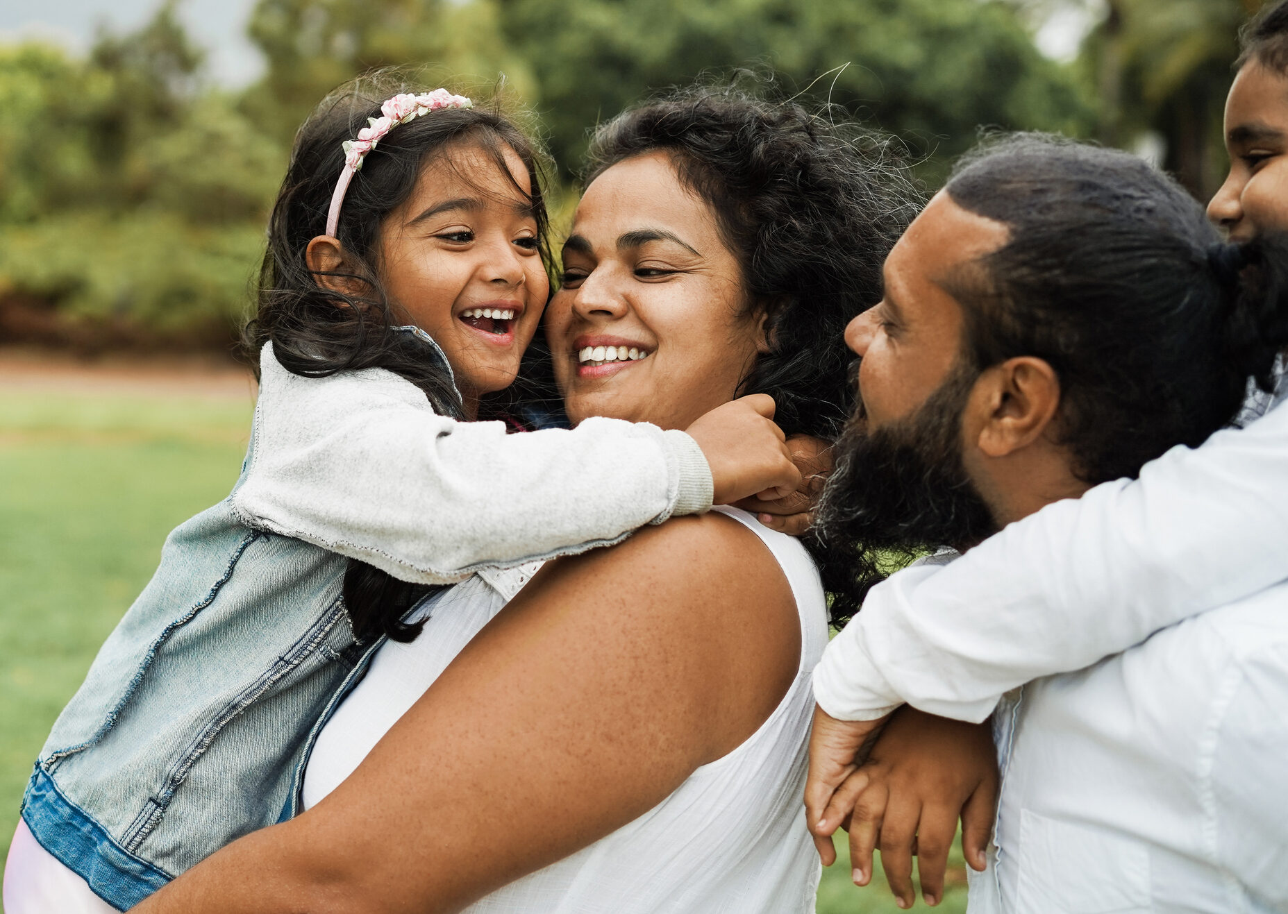 Happy indian family having fun outdoor - Hindu parents laughing with their children at city park - Love concept - Main focus on mother and daughter face