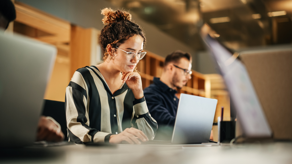 Enthusiastic young businesswoman working on a computer in a modern bright office.