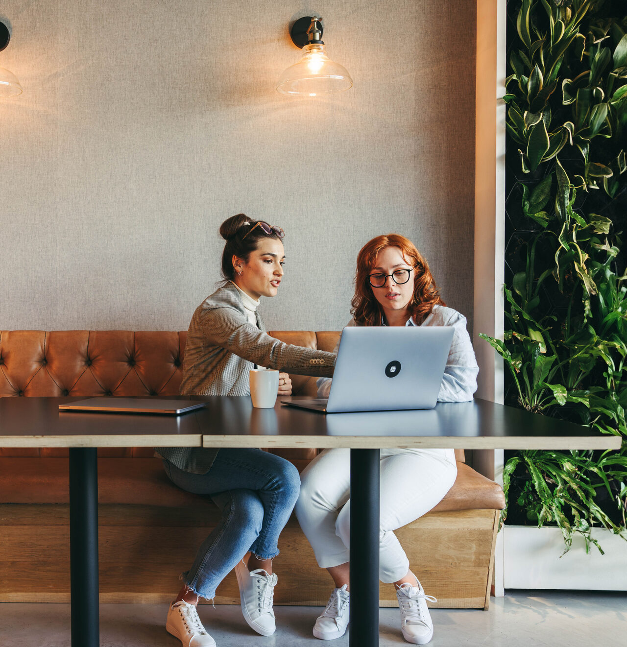 Professionals in a coworking space collaborate and discuss ideas. Businesswomen and coworkers work on laptops, engaging in discussions. They emphasize teamwork, analyze data, and develop software. workers office business